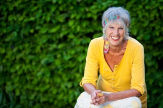 Portrait of happy senior woman sitting against creepers in park